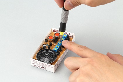小型の電子部品。キャラメル箱の中に様々な部品を組み立てると、丸いスピーカーから音が出るようになる（「子供の科学」編集部提供）