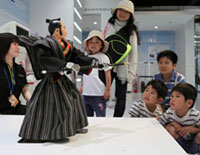 The Kuroda Bushi robot heroically performs to the Kuroda Bushi folk song at Robosquare. The head portion is made from a traditionally crafted Hakata doll from Fukuoka City and clad in traditional Hakata textile fabrics.