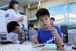 An elementary school student tries his hand at making a motor for a robot at a workshop in Tokyo. (Robotecs Lab, Akihabara, Tokyo)