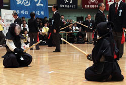 Kendo players squat facing each other, waiting silently for the match to start.