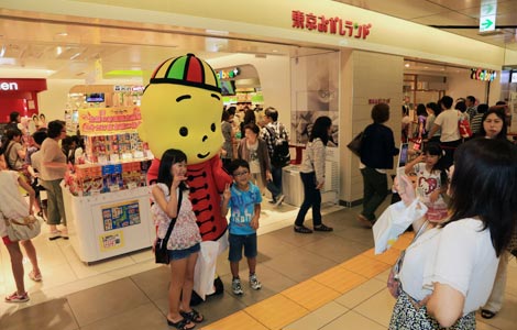 Children posing for a picture with a candy character at Tokyo Okashi Land.