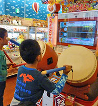 Children have fun pounding away on a taiko arcade game. The game shown here is “Taiko no Tatsujin” (Master Taiko Drummer) made by Namco Bandai Holdings.