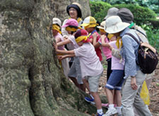 Children prepare to write haiku by blindfolding themselves in order to feel nature with their bodies at Shinjuku Gyoen National Garden.