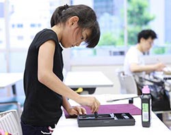 Elementary school girl making ink from sumi before taking up the brush (Cooperation with Hakushu Shodo Kai)