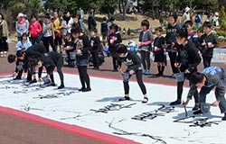 Team of elementary and junior high school students undertaking a calligraphy performance at an event (Provided by Ichijyukai, Souryu Koshio)