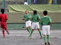 Youth team players race for the ball in a game of football.