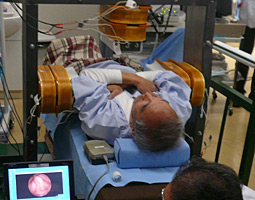 A patient lying within a magnetic field generator while the self-propelling capsule endoscope examines his digestive system