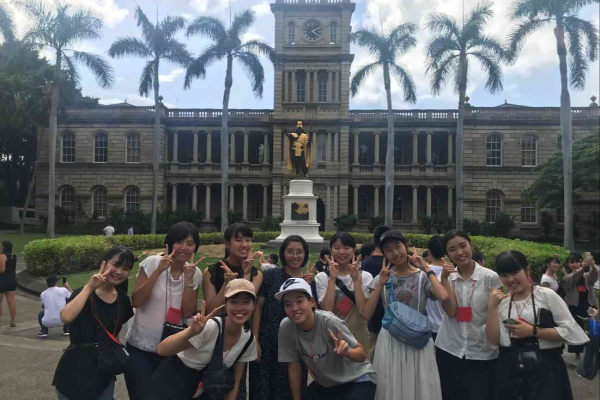 Students taking a photo in front of a statue of King Kamehameha.