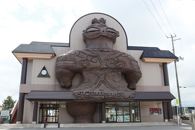Exterior of a public building in Kizukuri, Aomori Prefecture, featuring a giant Shako-chan statue inspired by a Jomon-period goggle-eyed clay figurine