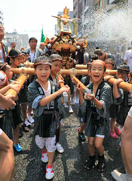 夏祭りを盛り上げるみこし行列。水をかけられてずぶ濡れになりながら元気にみこしを担ぐ子どもたち（深川八幡祭り）