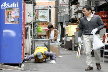 (On the left) Someone reaches under a drinks vending machine to get trash out. On the right, a participant is looking for trash holding a pair of tongs and a trash bag.