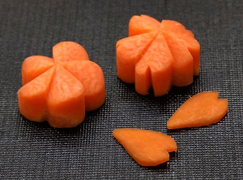 Plum blossom made of carrot (left) and cherry blossom (back right) and petals with carved tips（Tsuji Culinary Institute）