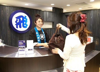 A staff member wearing a happi coat while handing over luggage at the Tokyo Service Center, located at Tokyo station. (courtesy of Sagawa Express)