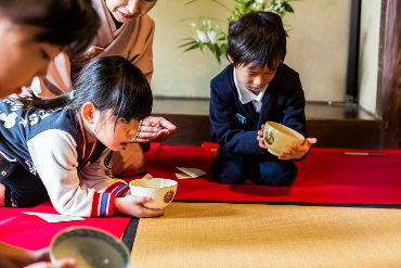 Los niños escuchan las explicaciones con expresión seria en la sesión de la clase de la ceremonia del té para niños (en el Museo de Arquitectura al aire libre Edo-Tokyo)