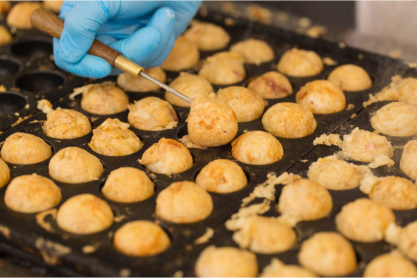 Takoyaki, bolas hechas con masa de harina rellenas de pulpo, fritas en una plancha de hierro.