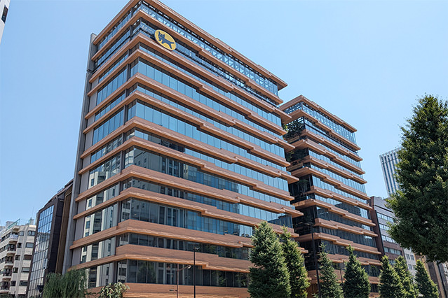 Exterior view of a modern office building in central Tokyo featuring extensive use of wood cladding combined with glass façades