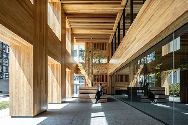 Interior space with exposed wooden columns and ceilings, featuring a seating area integrated into a warm, wood-clad architectural design